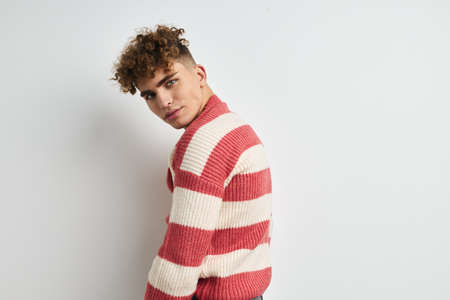 Attractive man in a striped sweater posing light backgroundの写真素材