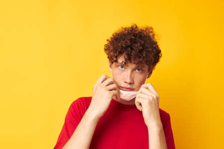 Young curly-haired man in a red t-shirt medical mask protection Lifestyle unalteredの写真素材