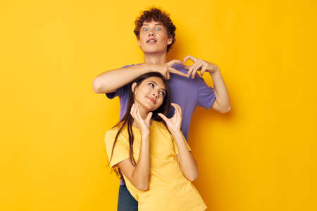 portrait of a man and a woman casual clothes posing emotions antics yellow background unalteredの写真素材