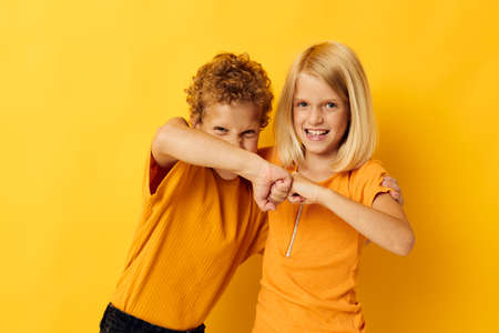 two joyful children in yellow t-shirts standing side by side childhood emotions yellow backgroundの写真素材