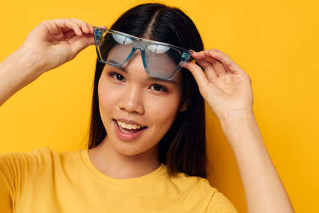 cheerful woman in yellow t-shirt and stylish glasses posing fashionの写真素材
