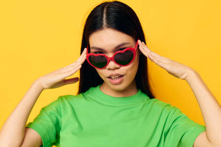Portrait Asian beautiful young woman in dark glasses in a green t-shirt posing modern yellow...