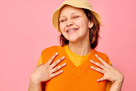 funny girl in an orange sweater in yellow hat hand gesture cropped view unalteredの写真素材