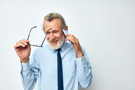 Senior grey-haired man talking on the phone business work isolated backgroundの写真素材