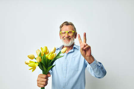 Portrait of happy senior man yellow bouquet of flowers posing isolated backgroundの写真素材