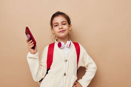 little girl with phone posing red backpack childhood unalteredの写真素材