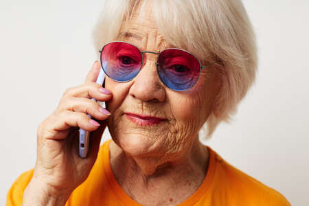 smiling elderly woman in casual t-shirt sunglasses talking on the phone close-up emotionsの写真素材