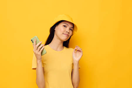 pretty brunette in a yellow hat and T-shirt talking on the phone studio model unalteredの写真素材