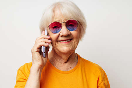 Portrait of an old friendly woman in a yellow t-shirt posing communication by phone close-up emotionsの写真素材