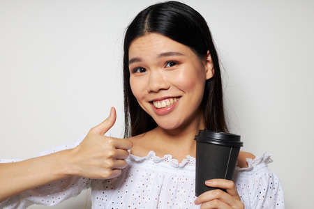 pretty brunette a black glass in the hands of a drink like a smile light background unalteredの写真素材