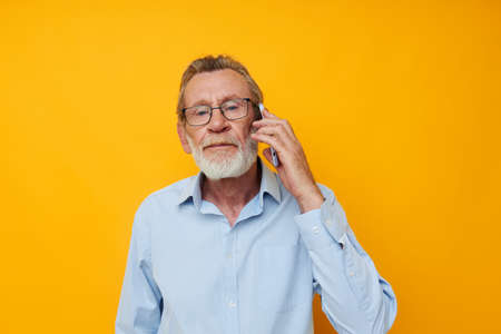 Portrait elderly man gray beard with glasses talking on the phone unaltered