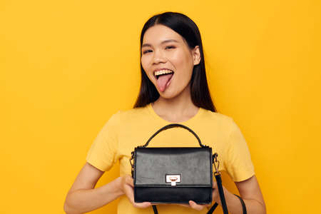 Charming young Asian woman in yellow t-shirts fashion posing female accessory yellow background unalteredの写真素材