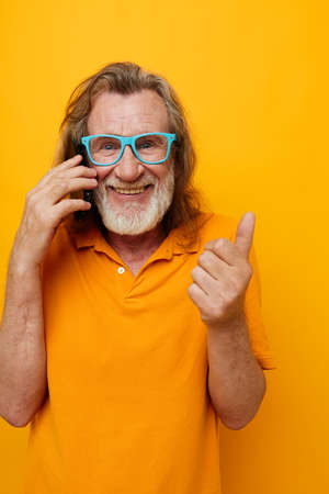 elderly man gray beard communication on the phone emotions yellow background