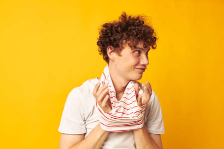 portrait of a young curly man putting on a striped t-shirt posing isolated background unaltered