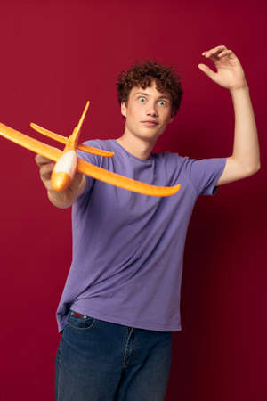 young guy with toy airplane entertainment red background unalteredの写真素材