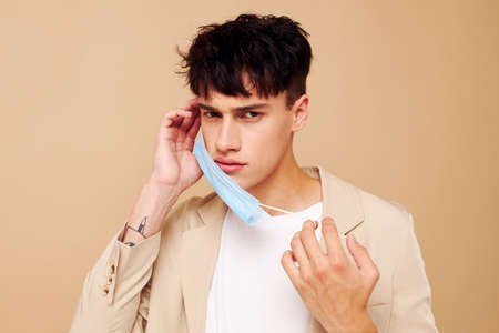 portrait of a young man in a medical mask in the hands of posing fashion isolated background...