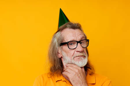 Senior grey-haired man in a yellow t-shirt with a cap on his head fun cropped viewの写真素材