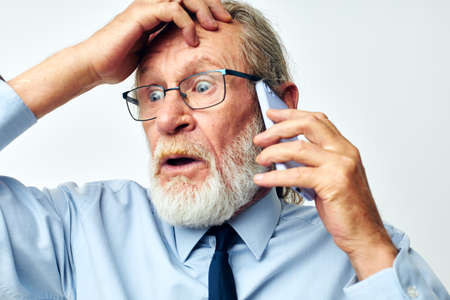old man with phone shocked in studio on white background