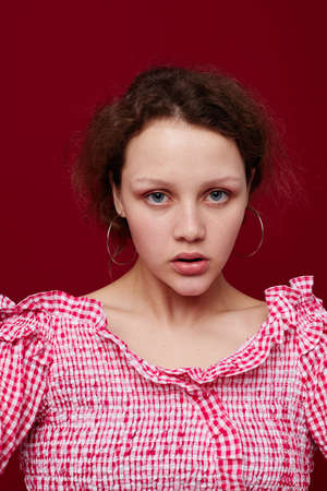cute young girl in pink shirt gesturing with her hands studio red background