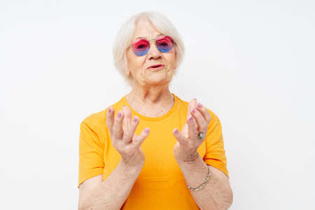 smiling elderly woman in a yellow t-shirt posing light background