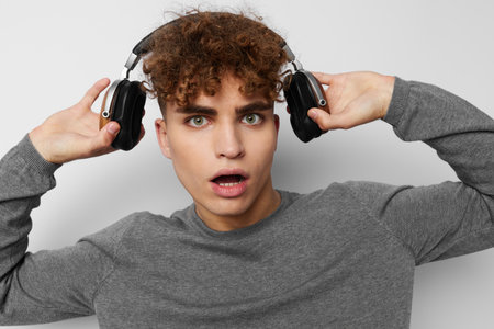 handsome guy in a gray sweater headphones fashion light background