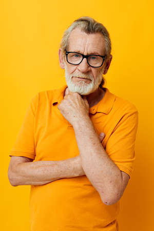 Photo of retired old man posing yellow tshirt glasses monochrome shotの写真素材