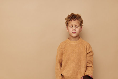 curly boy in a beige sweater posing fun childhood unaltered