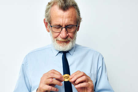 Portrait elderly man Bitcoin cryptocurrency in the hands of a financier isolated backgroundの写真素材