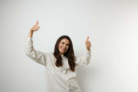 a beautiful happy woman gives a thumbs up white shirts on a white background with an empty space for...