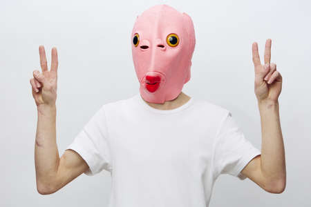 portrait of a man in a pink mask on his face showing numbers with his fingers looking at the cameraの写真素材