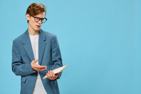 handsome young guy in a suit and glasses shows his hand at his notebook