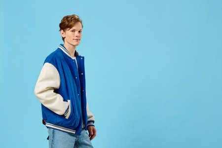 handsome, fashionable guy posing in a bomber jacket holding his hands in his pocketsの写真素材