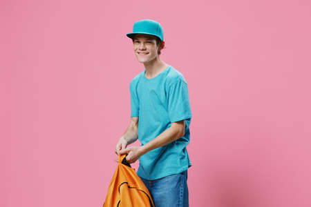 happy guy smiles with his teeth and looks at the camera while standing with a backpack in his hands