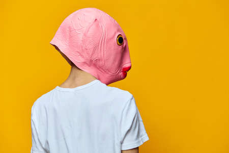 portrait of a man in a funny pink masquerade mask turning away from the cameraの写真素材