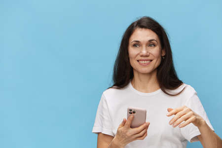 a beautiful sweet woman stands on a light blue background talking on the phone
