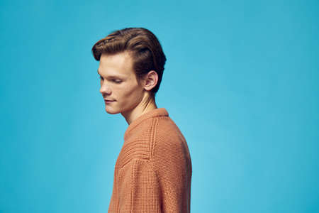 cute guy posing on a blue background standing sideways to the cameraの写真素材