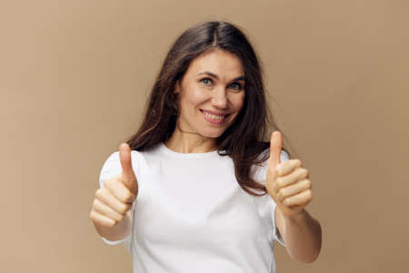 beautiful, happy woman standing on a beige background with long hair fluttering in the wind, stands...