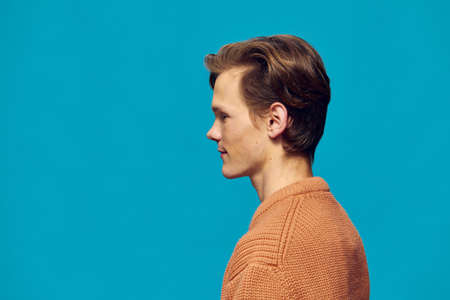 cute guy posing on a blue background standing sideways to the cameraの写真素材
