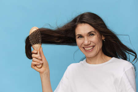 beautiful portrait. happy. attractive woman joyfully combing her long, shiny hair while standing on...