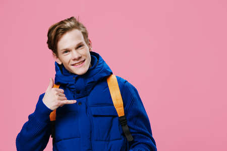 handsome attractive guy in winter outerwear and a backpack on his back asks with a gesture to call...