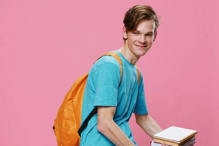 funny guy student with a backpack on his back leaning over holding textbooks in his handsの写真素材