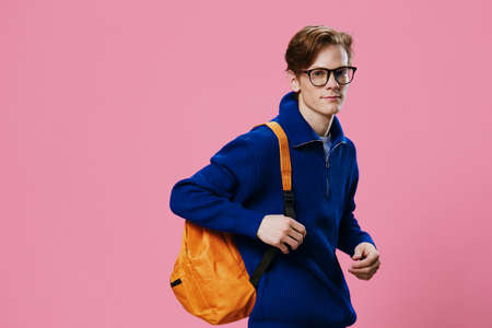 a young, handsome student in black-rimmed glasses, a blue sweater with a zipper and an orange...