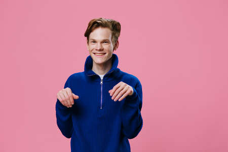 joyful, happy guy in a blue sweater posing funny with his hands folded