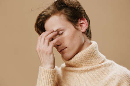 close portrait of a redhead guy with good looks and freckles on his face with his eyes closed.