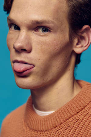 close portrait of funny guy with freckles showing tongue