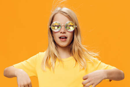funny, playful girl posing standing on a bright background in yellow clothes and shiny, carnival...