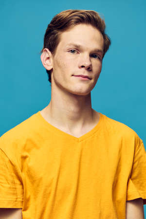 vertical portrait of a guy in a yellow T-shirt on a blue backgroundの写真素材