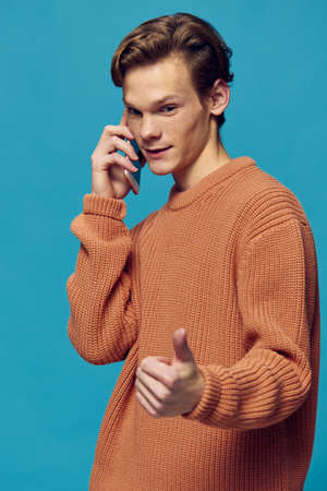 man talking on the phone while standing on a blue backgroundの写真素材