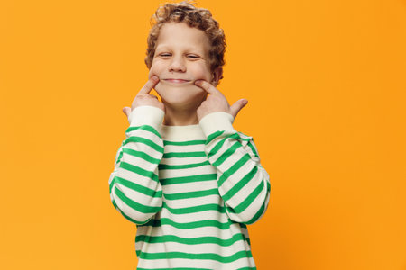 horizontal portrait of a cute, funny, playful, curly-haired boy of school age in a striped...