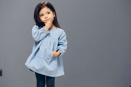 a girl in a blue dress stands with her hands in her pocketの写真素材